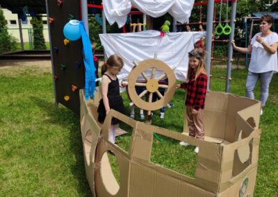 Dwoje dzieci pozuje w papierowym statku w ogrodzie