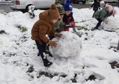 Dzieci toczą kule śnieżną