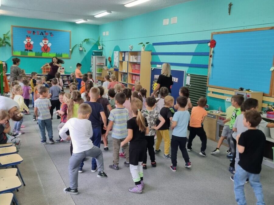 Dzieci wspólnie tańczą na sali