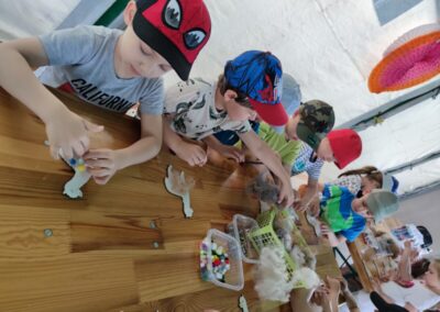 Dzieci wykonują pracę plastyczną dekorując drewnianą alpakę